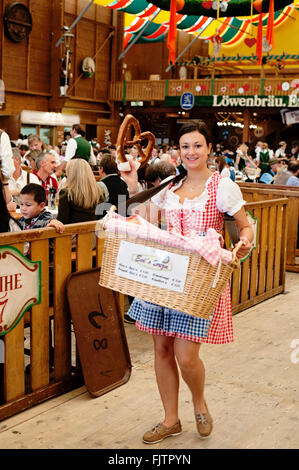 Verkauf von Brezeln am Oktoberfest im Inneren des Zeltes Loewenbraeu Mädchen Stockfoto