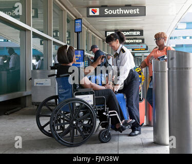 Ein Southwest Airline-Mitarbeiter hilft einen Passagier in einem Rollstuhl am Flughafen La Guardia in New York City. Stockfoto