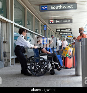 Ein Southwest Airline-Mitarbeiter hilft einen Passagier in einem Rollstuhl am Flughafen La Guardia in New York City. Stockfoto