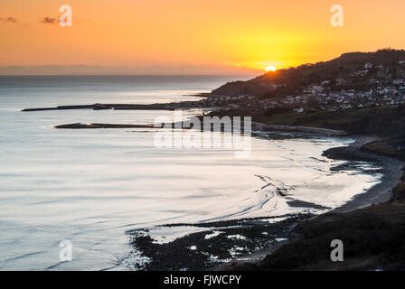 Die untergehende Sonne über Lyme Regis angesehen von Charmouth auf Dorset Jurassic Coast, UK Stockfoto