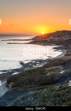 Die untergehende Sonne über Lyme Regis angesehen von Charmouth auf Dorset Jurassic Coast, UK Stockfoto