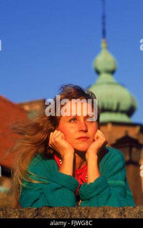 Gesundes und frisches Gesicht der Frau trägt bunte Pullover in Vorderseite der Mauer mit Kirchturm in Stockholm Stockfoto