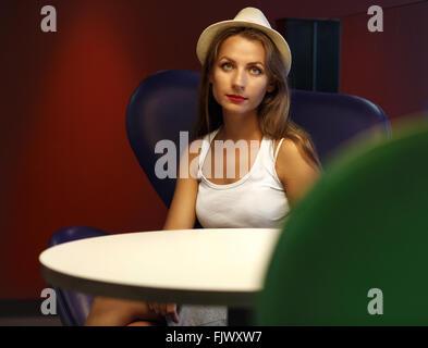 Junge hübsche Mädchen mit Hut sitzt auf dem Stuhl im café Stockfoto