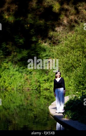 Dame im Wald, umgeben von Natur, See,, Wasserreflexion Stockfoto