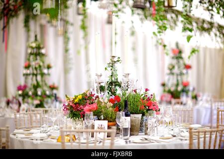 Hochzeit, Event oder besonderen Anlass Tisch Dekoration und Blumen, bunt, hell, Gänseblümchen, Rosen, Kristall Kronleuchter, Laternen Stockfoto