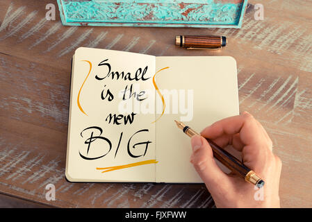 Retro-Effekt und getönten Bild einer Frau hand schreiben eine Notiz mit einem Füllfederhalter auf einem Notebook. Klein ist der neue große als Konzept Geschäftsbild handschriftlichen text Stockfoto