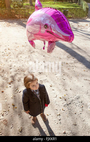 Glückliches kleines Mädchen hält einen großen Ballon Delphin geformt in einem park Stockfoto