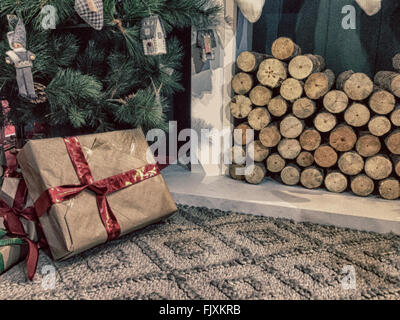 Geschenke unter dem Weihnachtsbaum in der Nähe von Kamin dekoriert Stockfoto