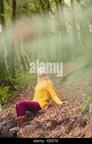 Schöne blonde Frau auf dem Boden sitzend Stockfoto