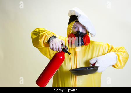 Reife Frau in gelb Hazmat Anzug und Köche Hut hält Pan und Feuerlöscher. Stockfoto