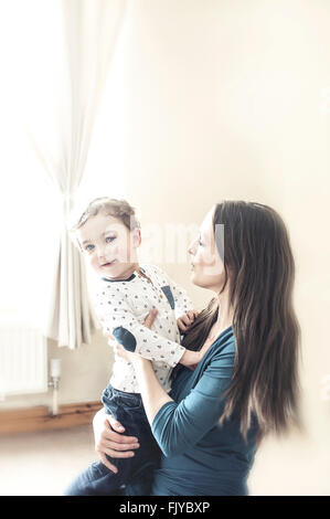 junge Mutter mit einem kleinen Jungen in ihren Armen zu Hause Stockfoto