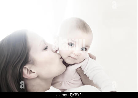 junge Mutter küssen ihr Babymädchen in armen Stockfoto