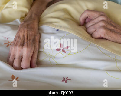 Die Hände einer sehr alten und dünne Frau im Bett Stockfoto