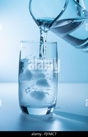 Gießen Wasser in Glas mit Eis
