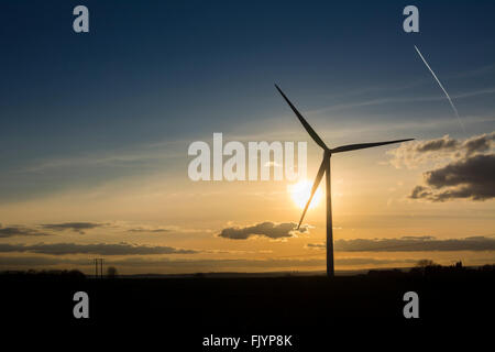 Wind-Turbine-Generator gegen Sonnenuntergang mit Flugzeug Con Trail Overhead. Stockfoto
