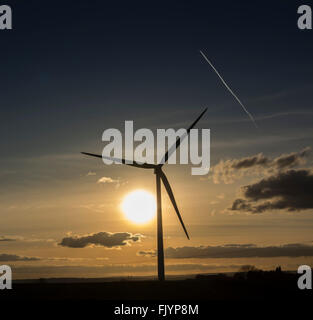 Wind-Turbine-Generator gegen Sonnenuntergang mit Flugzeug Con Trail Overhead. Stockfoto