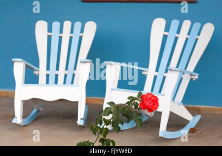 Rose wächst vor mit blauen und weißen traditionellen Schaukelstühlen auf Veranda in Vinales, Pinar del Rio Provinz, Kuba, Westindien Stockfoto