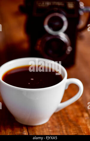 Nahaufnahme von einer Tasse Kaffee und eine alte Kamera auf einer rustikalen Holzoberfläche Stockfoto