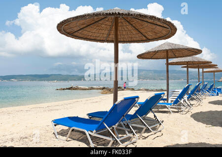 Sonnenschirme und leeren Liegestühlen am Sandstrand, Ammouliani oder Amoliani Insel, Stagira-sich, Chalkidiki, Griechenland Stockfoto