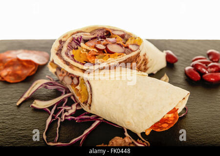 Mexikanische Tortilla mit Bohnen, Rindfleisch und Tomaten. Wickeln Sie halbieren mit gegrilltem Hähnchen und rot Kohl Salat Salsa. Schweinefleisch heißen Kulen S Stockfoto