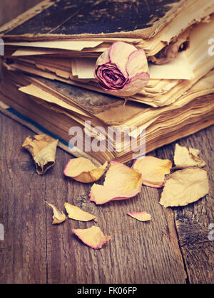Trockener rose und alte Bücher über alte hölzerne Grunge Hintergrund Stockfoto