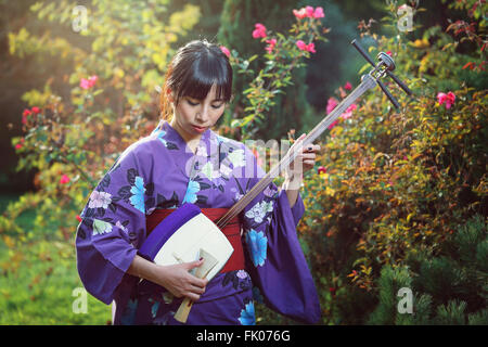 Schöne Japanerin traditionelle Musikinstrument zu spielen. Outdoor portrait Stockfoto