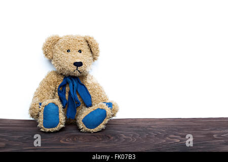 niedliche Teddy Bär sitzend auf Holzbrett isoliert auf weißem Hintergrund Stockfoto