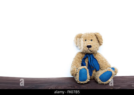 niedliche Teddy Bär sitzend auf Holzbrett isoliert auf weißem Hintergrund Stockfoto