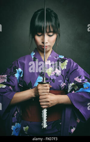 Samurai Frau bereit, mit Katana zu kämpfen. Dunkle Studioaufnahme Stockfoto