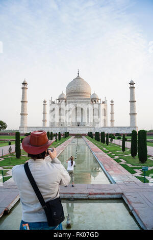 Agra, Indien. Männliche Touristen in einem roten Hut nimmt ein Bild des Taj Mahal spiegelt sich in seiner reflektierenden Pool. Stockfoto