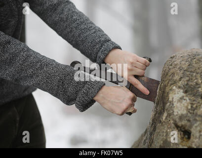 Hand des tapferen Ritters versucht, das magische Schwert Excalibur in den Stein zu entfernen Stockfoto