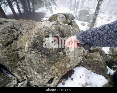 Hand des tapferen Ritters versucht, das magische Schwert Excalibur in den Stein zu entfernen Stockfoto