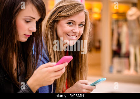 Zwei schöne Frauen, die mit ihrem Handy Stockfoto