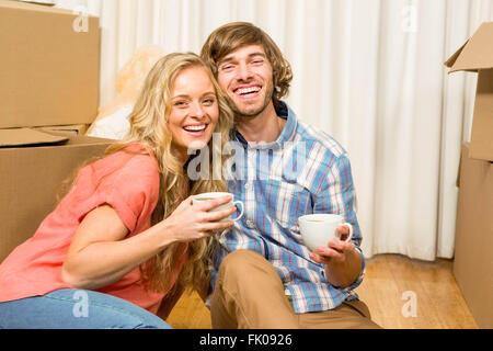 Süßes Paar sitzen auf dem Boden beim Trinken Stockfoto