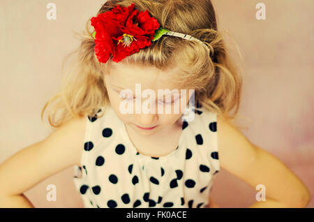kleines Mädchen mit geschlossenen Augen und roten Klatschmohn Blume im Haar Stockfoto