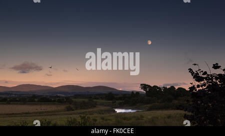 Eine fast vollständige Waxing gibbous Mond über dem machar Hügel und den Fluss Cree in der Nähe von Newton Stewart in Galloway, Schottland, Großbritannien. Stockfoto