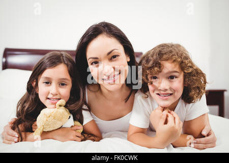 Glückliche Frau mit Kindern auf Bett zu Hause Stockfoto