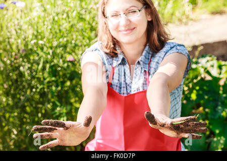 Reife lustige Bäuerin Kopftuch Schürze Hut im Garten Stockfotografie