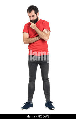 Junge Hipster im roten T-shirt streicheln Bart weiß denken und blickte. Ganzkörper-Länge-Porträt über weißen isoliert Stockfoto