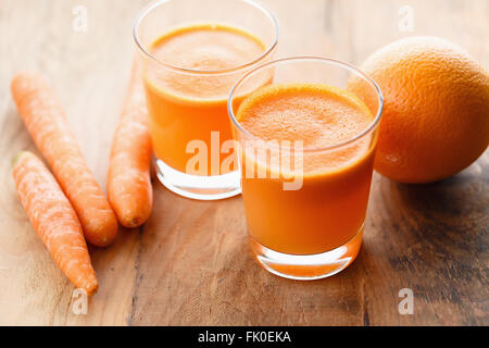 Frischen Karotten und Orangensaft auf Holztisch Stockfoto