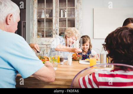 Lächelnde Oma und Enkelin beim Sitzen am Esstisch Stockfoto