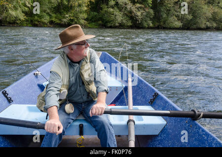 Ein alter Fischer sieht über das Wasser, wie er sein Boot rudert. Stockfoto