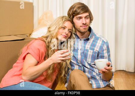 Süßes Paar sitzen auf dem Boden beim Trinken Stockfoto