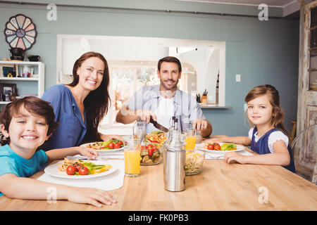 Porträt der glückliche Familie mit Essen am Esstisch Stockfoto