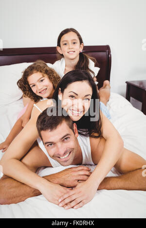 Porträt der fröhlichen Familie auf Bett liegend Stockfoto