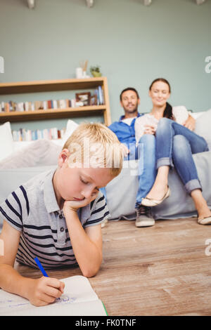 Junge auf Buch, während die Eltern ihn ansah Stockfoto