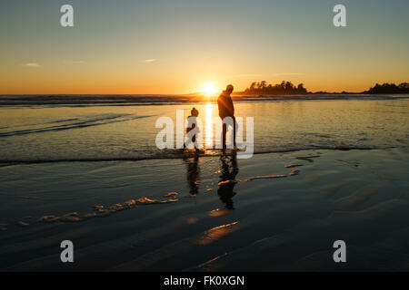 Vater und Sohn gehen in der Brandung am Strand Chesterman in Tofino, Britisch-Kolumbien Stockfoto