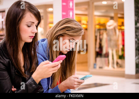 Zwei schöne Frauen, die mit ihrem Handy Stockfoto