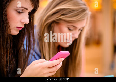 Zwei schöne Frauen, die mit ihrem Handy Stockfoto