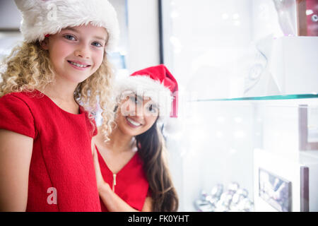 Mutter und Tochter in Weihnachten Kleidung lächelnd in einem shop Stockfoto